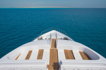 Sticker - View over the bow of a large luxury motor yacht on tropical open ocean with sun beds