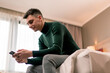 © Guys Who Shoot - a young guy in the room of a luxury hotel room holds a smartphone in his hands and solves business issues after a trip