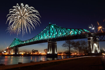 Wall Mural - Fireworks explode over bridge, reflection in water. Montreal’s 375th anniversary. luminous colorful interactive Jacques Cartier Bridge. Bridge panoramic colorful silhouette by night.