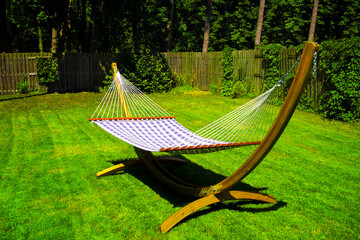 Poster - Sunny wooden hammock standing in green garden.