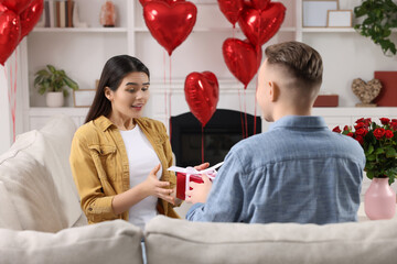 Poster - Woman receiving gift box from her boyfriend at home. Valentine's day celebration.