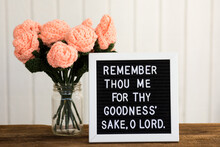 A Bible Verse On A Sign Board With Crocheted Flowers
