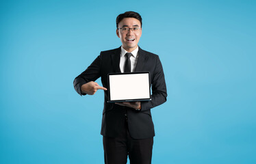 Wall Mural - image of asian business man using laptop on blue background.