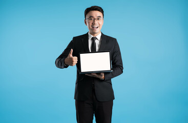 Wall Mural - image of asian business man using laptop on blue background.