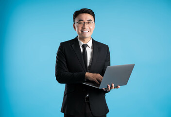 Wall Mural - image of asian business man using laptop on blue background.