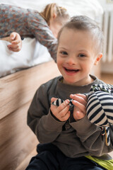 Wall Mural - Boy plays with his younger sister on the bed in home bedroom. Down syndrome and ASD