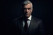 © Rudsaphon - Portrait of mature businessman in suit looking at camera on black background.Generative Ai