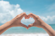 © ant - Hand do heart shape mean love on nature summer beach and blue sky background.