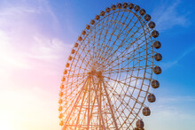 High Ferris Wheel At Sunset Or Sunrise With Cloudy Sky Background.