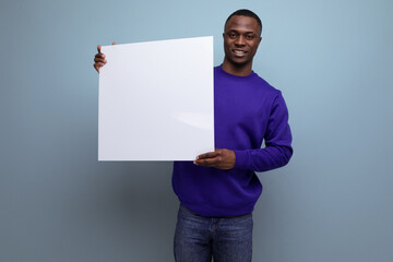 Wall Mural - successful handsome young american business man in blue sweatshirt holding white placard mockup