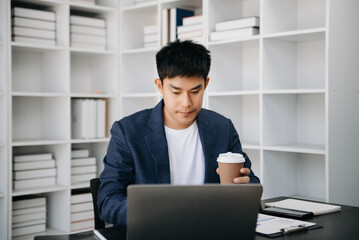 Asian business man executive manager looking at laptop watching online webinar training or having virtual meeting video conference doing market research working .