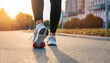 © Uuganbayar - Girl runner makes a morning run in a city street. Sneaker shoes, feet close-up. Jogging, running, wellness, fitness, health concept. Blurred background, Sunset sunrise light