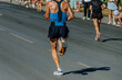 © sports photos - rear view male runner running city marathon, hot weather sweat on his back