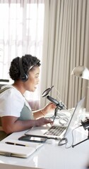 Wall Mural - vertical video of happy african american woman audio broadcasting from home, slow motion
