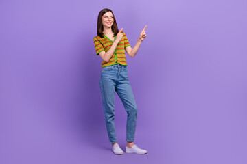 Poster - Full length photo of cheerful adorable lovely lady wear trendy clothes hands demonstrate empty space isolated on purple color background