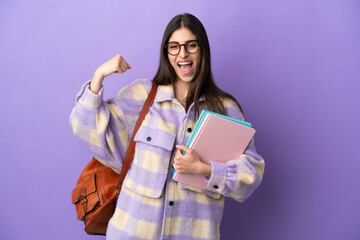 Wall Mural - Young student woman isolated on purple background doing strong gesture