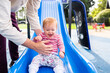 © Austockphoto - Baby laughing and being caught by father at playground slippery dip