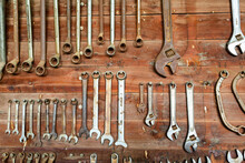 Rust Speckled Tools Hanging Neatly In Place On Farm Shed Wall