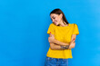 Young woman standing over blue background hugging oneself happy and positive, smiling confident.