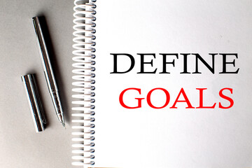 DEFINE GOALS text on a notebook with pen on grey background