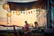 © luckybusiness - Young couple talking and laughing. Sunset in front of camper rv. Travel, fun, love, togetherness, lifestyle concept.