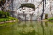 Lovely view of the famous lion monument carved in stone in a park with a pond in Lucerne. The landmark of Lucerne is dedicated 