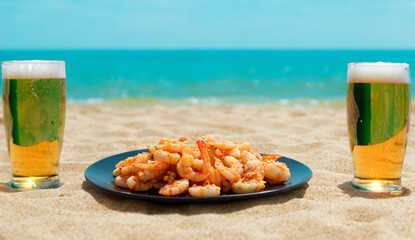 Two glasses of beer by the sea. Plate of food on the beach with delicious appetizer. Perfect vacation.