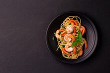 Stir-fried Spaghetti Or Stir-fried Noodles Tomato Sauce And Prawns On A Black Plate On A Wooden Table Background. Top View.