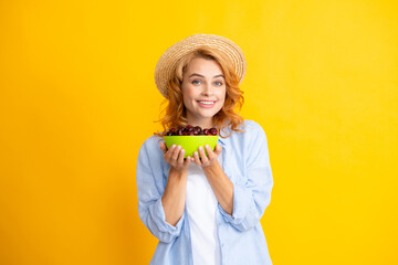 Wall Mural - Portrait of woman with cherries on yellow studio isolated background.