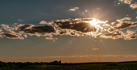 Wall Mural - A View of the Late Afternoon Sun Playing Peek a Boo with Clouds on a Summer Day