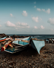 Fishing boats resting on the shore of Arher Beach in Socotra, Yemen, with the ocean and a partly cloudy sky in the background.