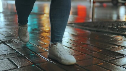Wall Mural - legs of a girl taking a step into a puddle on the street of a night city