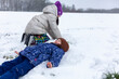 © PeterPike - Mother and daughter lying on the snow in winter park. Winter fun.