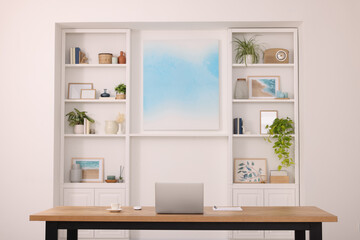 Canvas Print - Interior design. Cosy workplace with laptop on wooden table near abstract picture between shelves