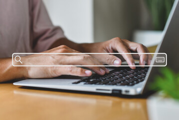 Man working on desk at home office hand on keyboard with searching bar icon. He is using technology to search for information on the Internet.