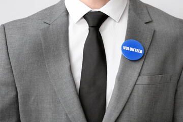 Canvas Print - Male volunteer with badge on light background, closeup