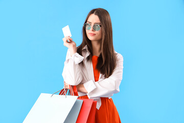 Sticker - Thoughtful young woman with gift card and shopping bags on blue background