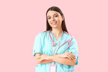 Female medical intern with stethoscope on pink background