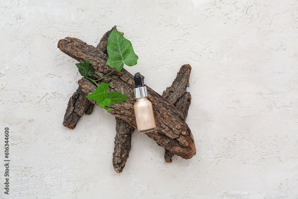 Bottle of highlighter with leaves and tree bark on white background