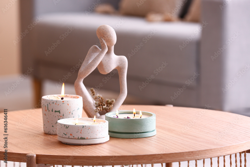 Holders with burning candles and decor on table in room, closeup
