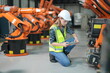 © FotoArtist - Robotic Arm engineer check on equipment in its with software of an Artificial Intelligence, Programming development technology work. Female industrial engineer working at automated robotic factory..