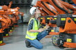 © FotoArtist - Woman working intently on a complicated industry 4.0 robot plant in technology factory.