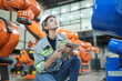 © FotoArtist - Portrait of Female Automotive Industry 4.0 Engineer in Safety Uniform Using Laptop at Car Factory Facility. Assembly Plant. engineer working at automated AI robotic production factory..