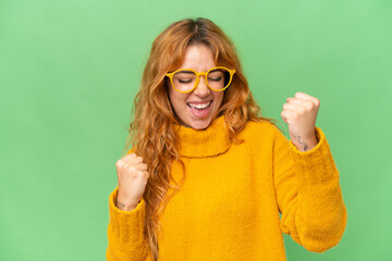 Wall Mural - young caucasian woman isolated on green screen chroma key background with glasses and celebrating a 