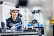 © FotoArtist - Mechanical engineers with robotic welder., Programming development technology work. Female industrial engineer working at automated AI robotic production factory