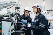 © FotoArtist - Mechanical engineers with robotic welder., Programming development technology work. Female industrial engineer working at automated AI robotic production factory