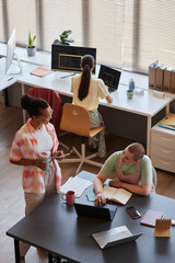 vertical high angle portrait of all female business team working in office with pink color accents