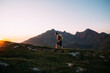 Fit and healthy young man walk up mountain in Norway at sunset. Midsummer sun light go over crest of valley. Concept outdoor lifestyle and adventure in nature