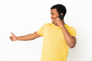 Canvas Print - African American handsome man using mobile phone over isolated white background giving a thumbs up gesture