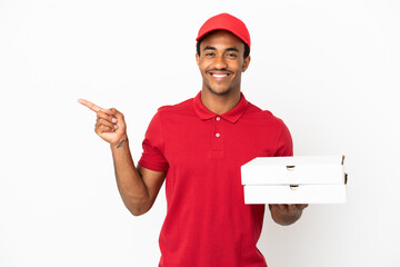 Wall Mural - African American pizza delivery man picking up pizza boxes over isolated white wall pointing finger to the side